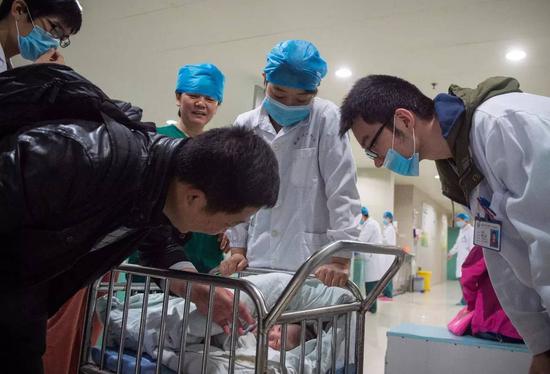 安徽医科大学第一附属医院产房外，助产士将一个刚出生的婴儿送到父亲身边（2016年4月8日摄）。 新华社记者 郭晨 摄