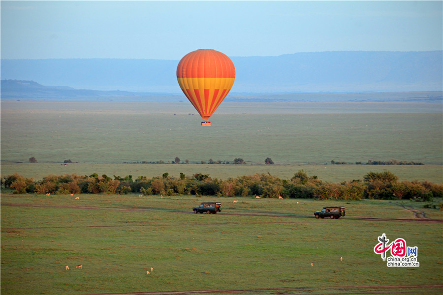 热气球飘荡在上空，草原上两辆四驱车缓缓驶来