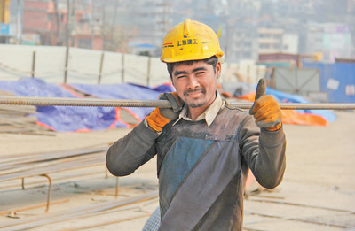 正在施工現場的尼泊爾建築工人坦卡扛著鋼筋,對記者豎起大拇指.