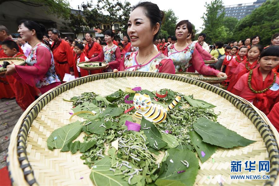 5月5日,一位市民托着泥猫守蚕竹匾参加传统的送春迎夏仪式