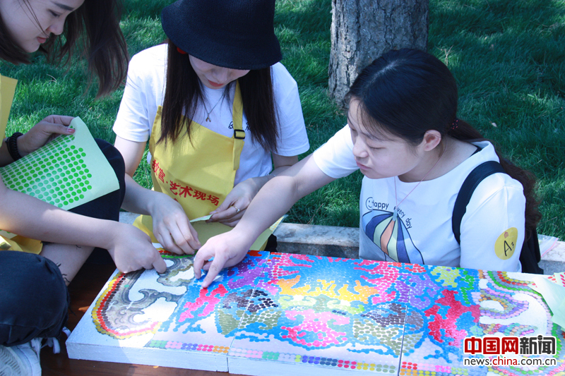 5月18日，国际博物馆日，故宫博物院在故宫箭亭南侧广场举办“让瓷母时尚起来”的活动。活动与正在故宫陶瓷馆展出的著名文物清乾隆各色釉彩大瓶相结合。参与活动的是20名18至30周岁的青年朋友。这些喜爱艺术的年轻人分作数组，以软陶、马赛克、点拼等多种手法，拼贴制作一个“时尚的瓷母”。 摄影 中国网 苏向东