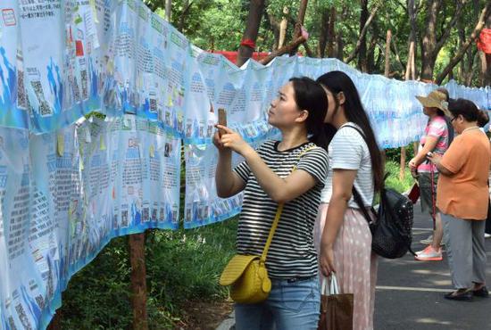 资料图片：一名市民在济南千佛山公园举行的“七月七相亲大会”上用手机记录相亲信息。新华社记者 徐速绘 摄