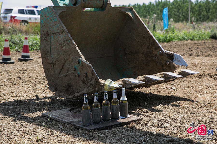 在挖掘机的铲斗上绑上改锥,刘二伟能轻松地在短时间内将啤酒瓶盖起开.