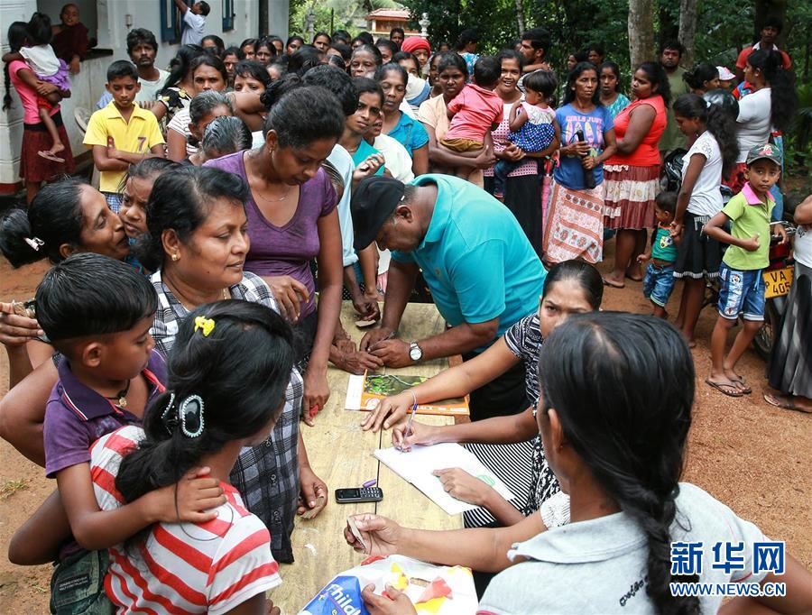 在斯里兰卡科伦坡附近的亚巴拉鲁瓦村，当地居民排队登记领取中国机械设备工程股份公司阿塔纳水厂项目组提供的赈灾物资。