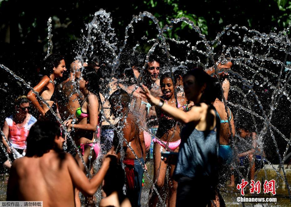 图为马德里民众在曼萨莱斯河边的喷泉下冲凉解暑。