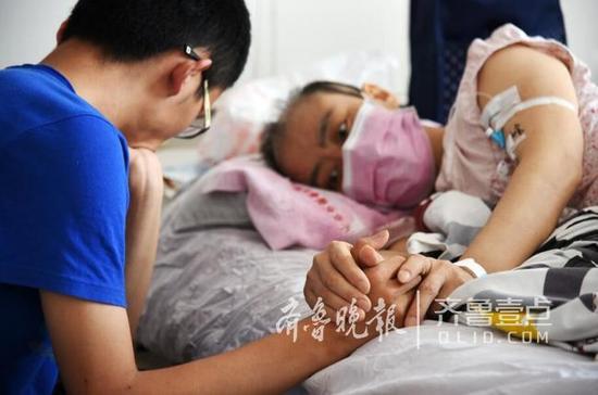 躺在病床上的母亲紧紧地牵着儿子的手臂,眼神里有太多的牵挂和不舍。