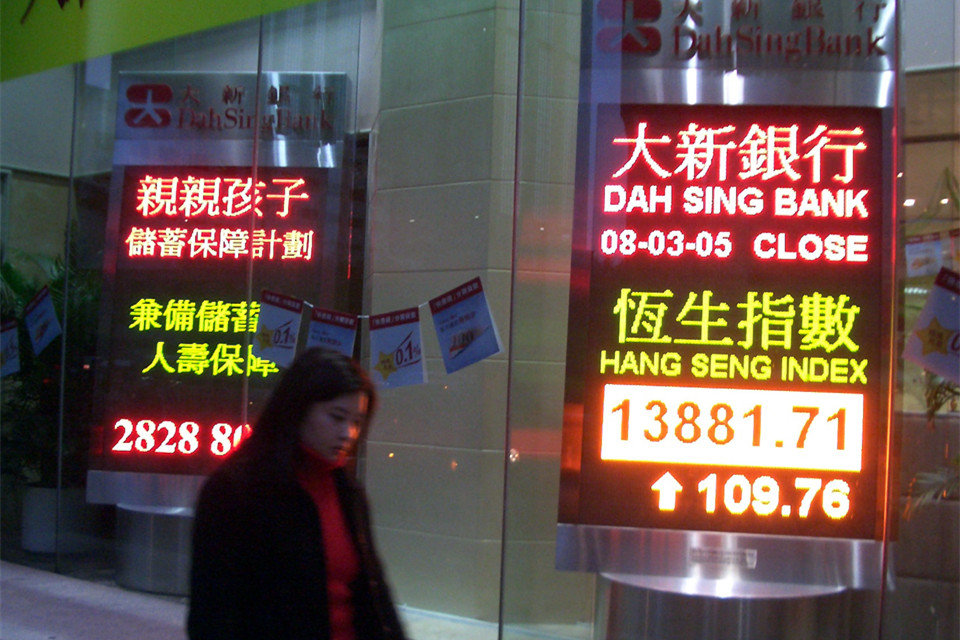 行人在香港股市恒生指数显示牌前走过