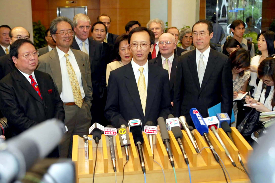 2003年5月23日，香港特区财政司司长梁锦松（前中）等部分政府官员及香港当地和驻港外国商会会长共同出席在政府合署举行的记者会，会上梁锦松表示，重振香港经济刻不容缓。
