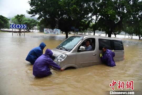 7月2日,一辆车辆在柳州市滨江路被泡,市民忙着推车。 王以照 摄