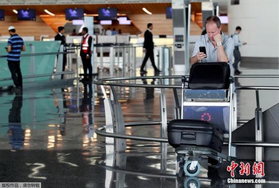 此前，阿联酋航空、埃及航空等相继暂停往返卡塔尔首都多哈的航班，沙特等国甚至禁止卡塔尔航空班机越过领空，令中东航空枢纽多哈的哈马德国际机场陷入混乱。图为一名游客在哈马德国际机场看手机。