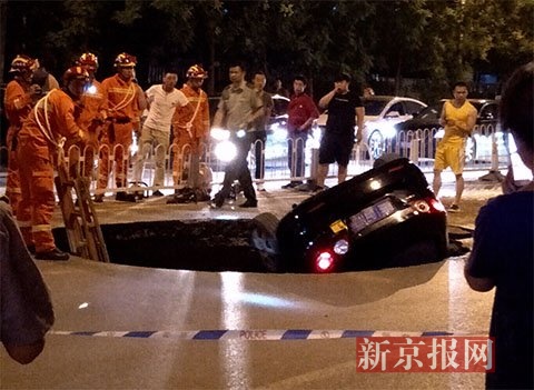  7月25日晚，西二旗大街路面突然塌陷，一辆黑色轿车坠入坑内，救援人员在现场救援。