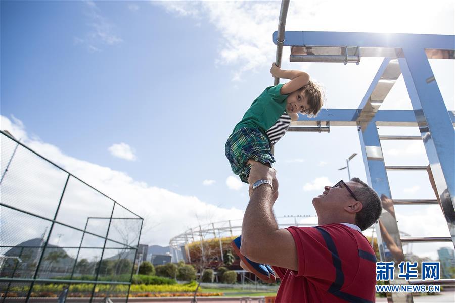 8月5日，一名父亲带着孩子在里约奥运公园内体验运动设施。