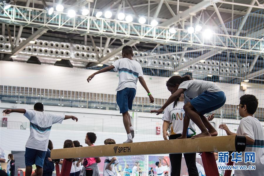 8月5日，当地孩子们在里约奥运公园内的三号里约人场馆内体验平衡木。