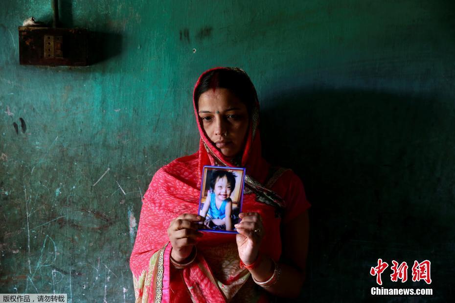 图为一位妇女捧着自家孩子的照片，她的孩子死于医院的缺氧事件。