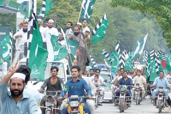 14日，巴基斯坦民众驾摩托车、举国旗庆祝祖国独立70周年。