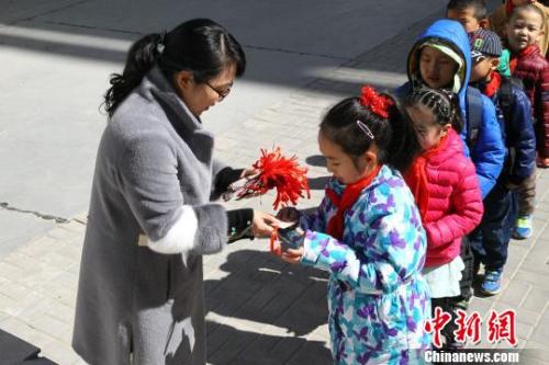 资料图：西宁市劳动路小学的校长们给学生赠送印有校风校训的书签。张海雯 摄
