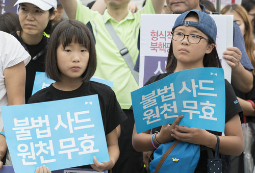 资料图片：7月31日，在韩国首尔国防部门前，韩国民众高举反对部署“萨德”系统的标语参加抗议集会。新华社发