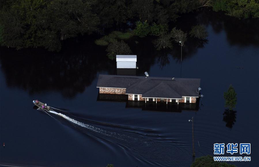 这张9月1日的航拍照片显示，一艘小船从美国得克萨斯州休斯敦一处被洪水围困的房屋旁经过。