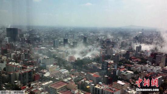 一名市民在墨西哥城地标建筑拉丁美洲塔(Torre Latina)上，用手机拍下了地震后的墨西哥城，建筑倒塌导致城内浓烟四起。