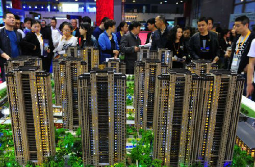 资料图：参观者在江苏无锡举办的房展会上观看一家房地产商的楼盘模型。