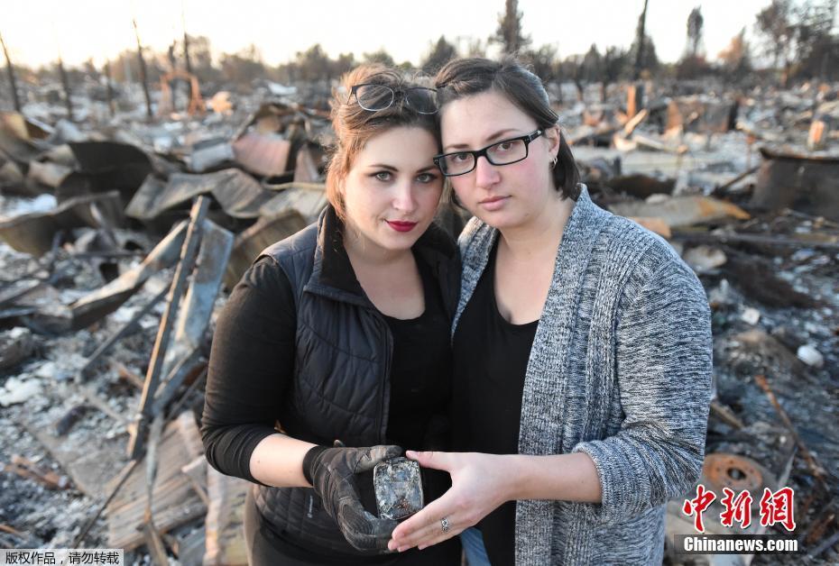 图为Michelle Ross（左）和Stephanie Staykow（R）在被烧毁的家园前合影。