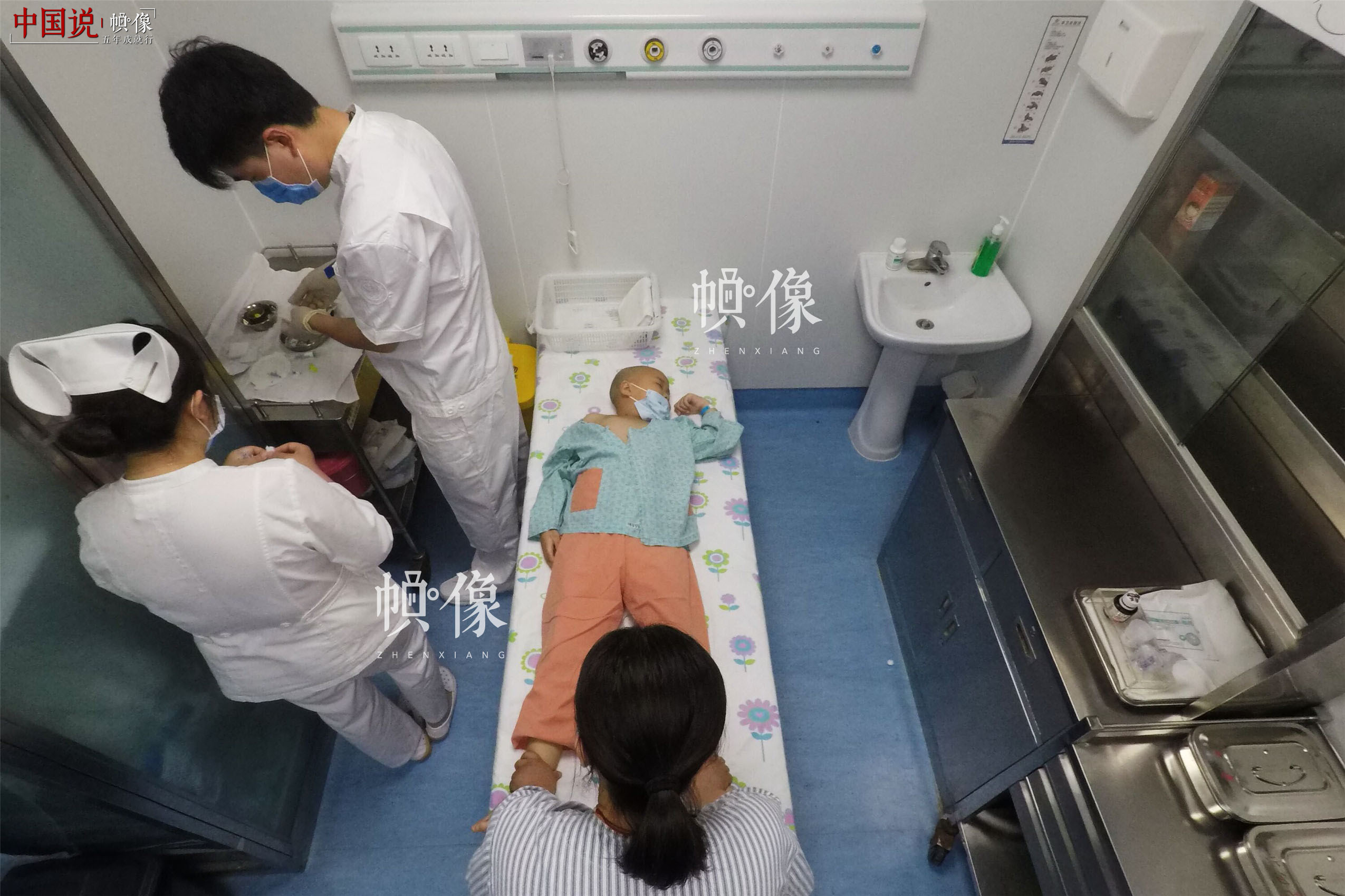 2017年5月24日，北京首都儿科研究所，男护士季长绪准备给白血病患儿天佑做检查。2017年4月28日，6岁的天佑被诊断为急性淋巴细胞白血病。白血病已成为危害儿童健康的重大疾病之一。目前中国每10万人中就有4-6人患有白血病，每年新增约4万名白血病患者，其中40%是儿童，并以2-7岁居多。中国网记者 陈维松 摄