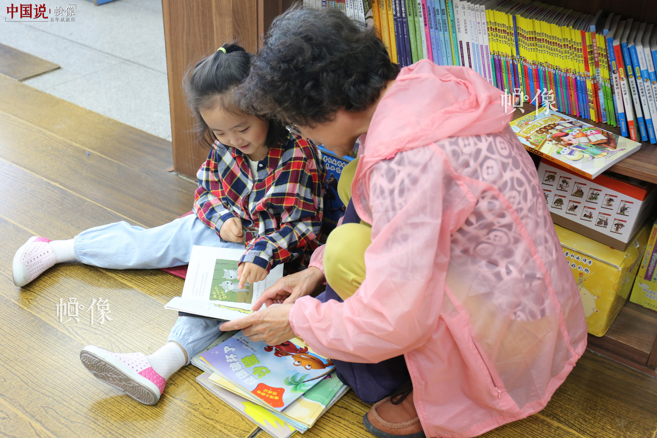 5月23日，北京三联书店美术馆店，一位老者给孙女读书。 中国网记者 赵超 摄