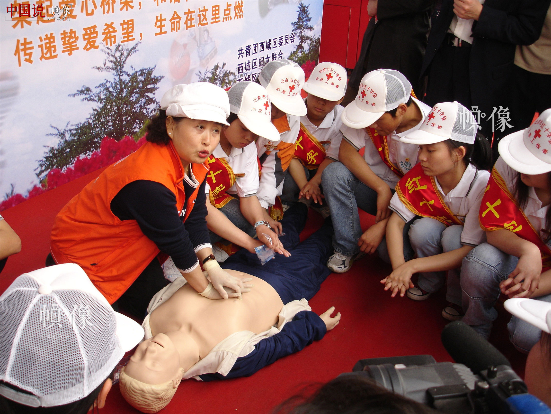  2006年5月7日，西城区红十字会在西单开展“五八”红十字日宣传活动，图为老师为过往群众和志愿者介绍应急救护知识。（西城区红十字会供图）