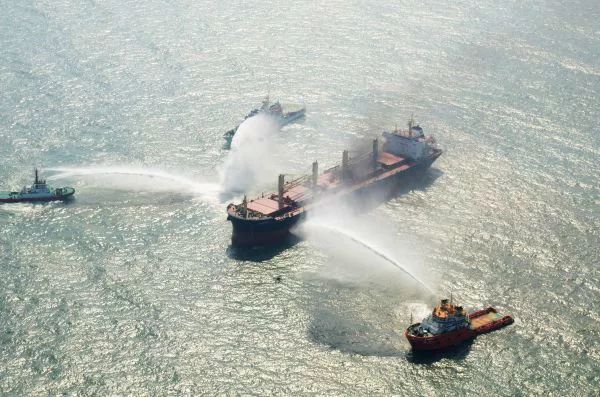 ▲救援船只在演练中对货轮进行喷水“灭火”。 （新华社）