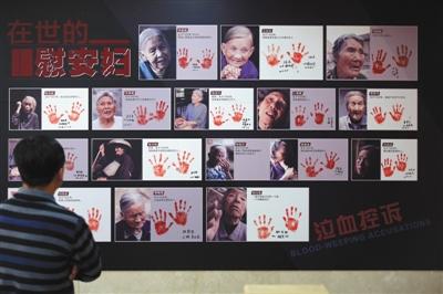 2016年12月10日，中国人民抗日战争纪念馆，观众在观看纪实画册《90位幸存慰安妇实录》展示的书中照片。画册揭露“二战”时日军的反人类罪行。