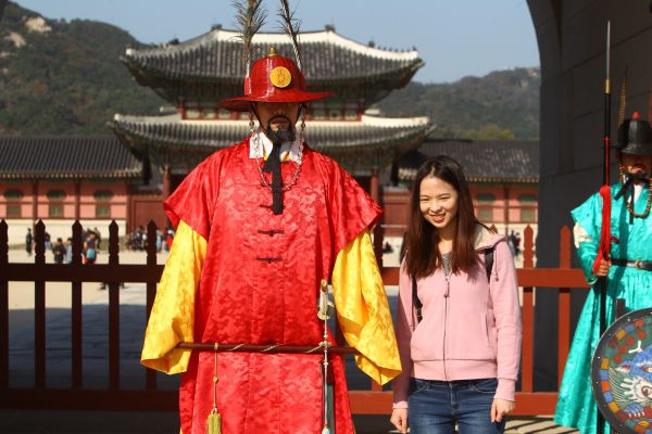 资料图片：在韩国首尔景福宫外，中国游客与韩国守城门将合影。 新华社记者姚琪琳摄