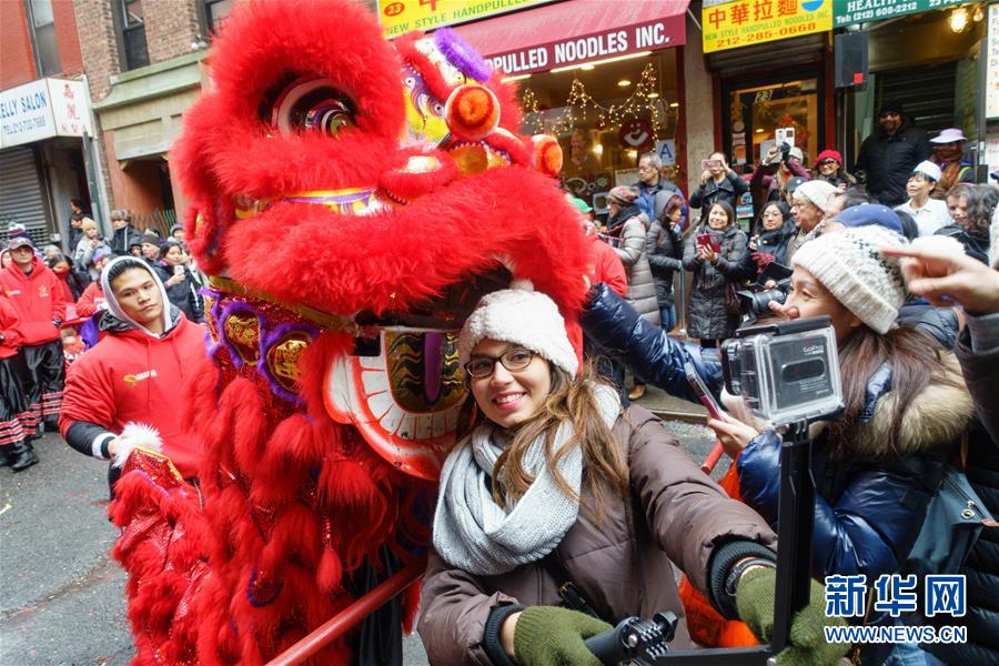 2016年2月8日，一名女子在美国纽约曼哈顿中国城与舞狮自拍。2016年农历新年大年初一，是美国纽约市第一个法定春节假日。