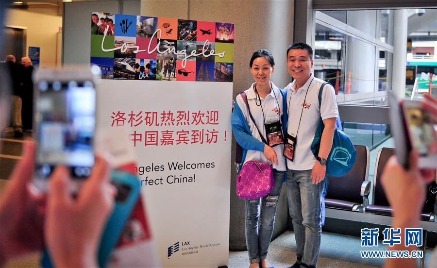 2014年5月22日，在美国洛杉矶国际机场，两名旅游团成员与洛杉矶会议及旅游局打出的欢迎标语牌合影留念。