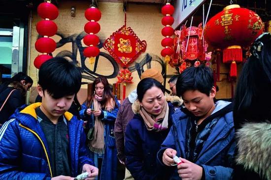 第二代第三代移民的生活方式已经越来越接近美国人,但很难说清究竟是谁影响谁更多一些。墙上的涂鸦和传统的灯笼融合在一起,人们低头查看着自己一年的运势。