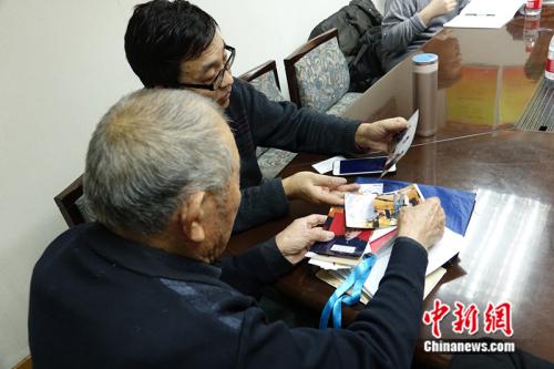 闫玉成向童增展示自己近年来收集的与索赔相关的照片、材料。 中新网记者 张尼 摄
