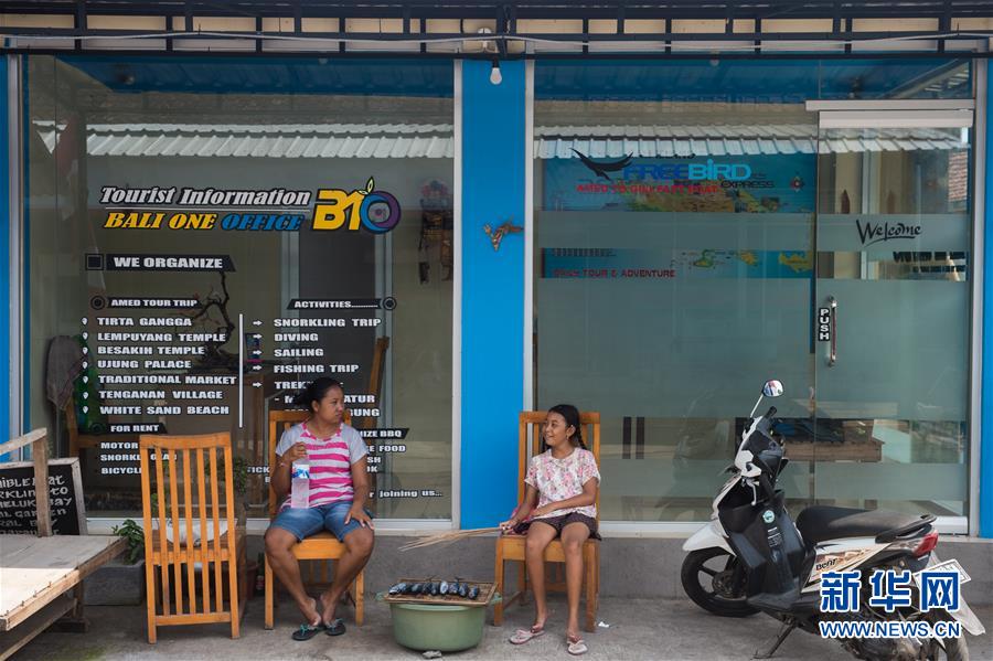 12月5日，在印度尼西亚巴厘岛阿贡火山附近的艾湄地区，当地居民坐在一家歇业的旅游店铺门前。