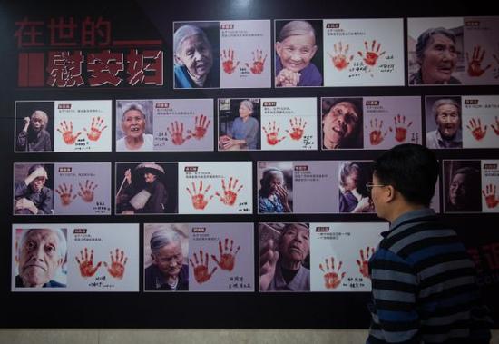 资料图片：2016年12月10日，一名与会者在观看纪实画册《90位幸存慰安妇实录》首发现场展示的书中照片。新华社记者 罗晓光 摄