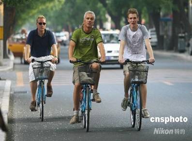 Près de la Cité Interdite, trois étrangers visitent la ville de Beijing à vélo