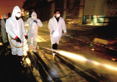 Quelques employés en uniformes de protection en train de désinfecter le marché Xinggong du bourg de Yanjiao où Huang Yanqing avait acheté des canards.