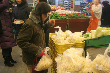 Des clients dans un supermarché, en train d'acheter des galettes de printemps et des germes de soja.