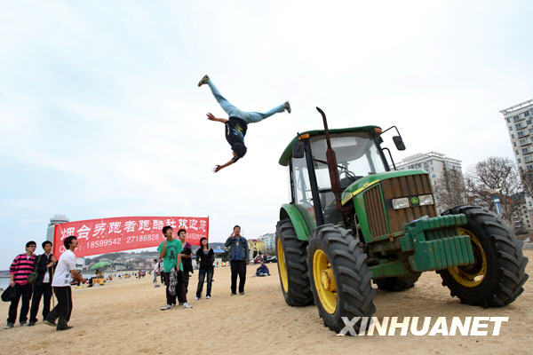 Photo : le 11 avril, un pratiquant du parkour effectue un salto arrière depuis le toit d’un tracteur, sur la plage de Yantai dans la province du Shandong (est de la Chine)