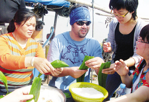 Le 22 mai, un professeur étranger de l&apos;Université des Sciences et Technologies du Jiangsu en train de préparer des zongzi avec des pêcheurs locaux.