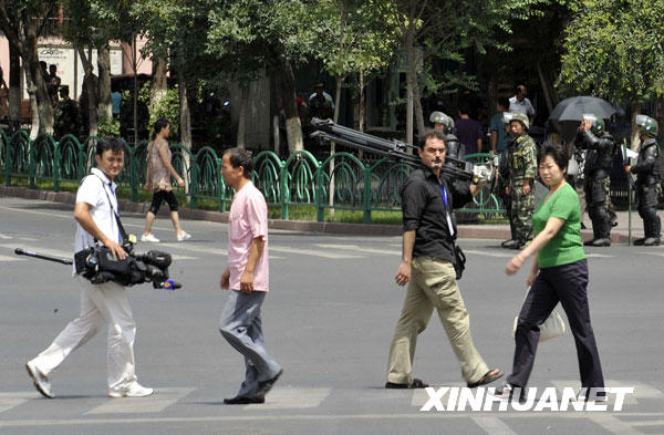 Le 8 juillet, deux journalistes étrangers transportent des équipements photographiques dans une rue d'Urumqi.