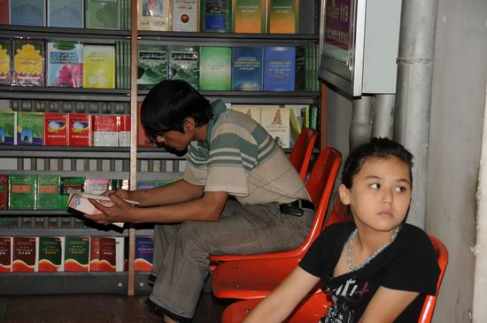 Un jeune homme ouïgour en train de lire.