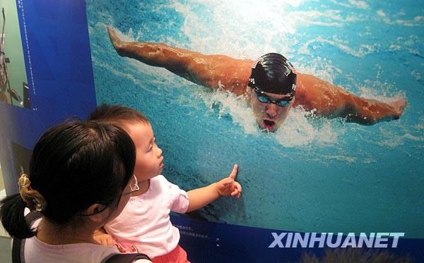 Une jeune mère portant sa fille dans les bras contemple une photo de Michael Phelps.