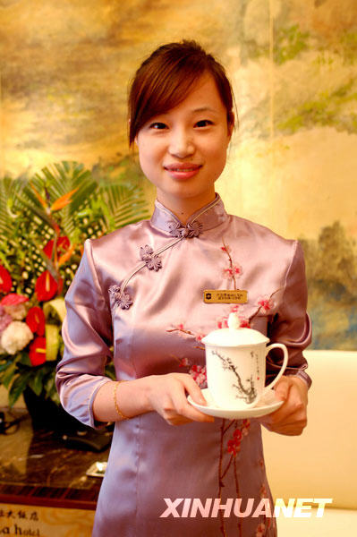  La robe chinoise pour la serveuse et la tasse imprimée d'un lavis chinois pour les hôtes. 