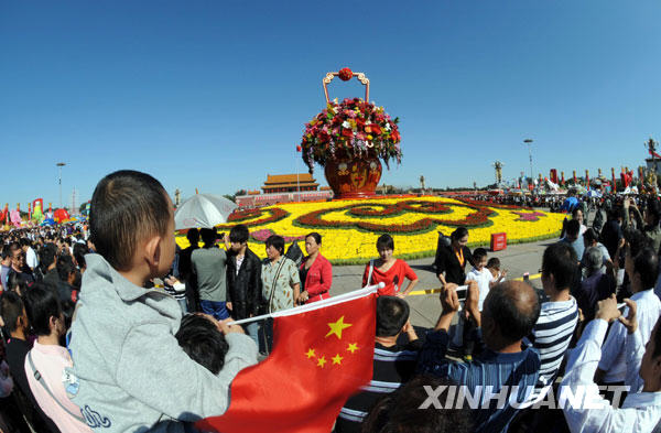 Le 3 octobre, des touristes prennent des photos devant les parterres de fleurs sur la place Tian&apos;anmen.