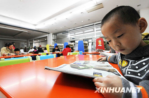 Dans la salle de la bibliothèque, un garçon lit un livre.