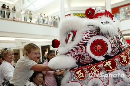 Une visiteuse dépose une ' enveloppe rouge ' dans la bouche du lion, symbole d'une bonne année.