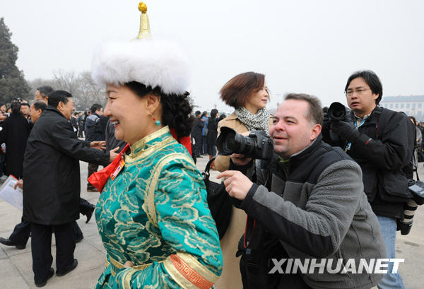 Avant la cérémonie d'ouverture, un journaliste étranger suit un membre de la CCPPC originaire d'une ethnie minoritaire. 